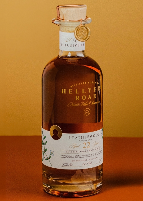 Bottle of Hellyer Road Leatherwood whisky on an orange background